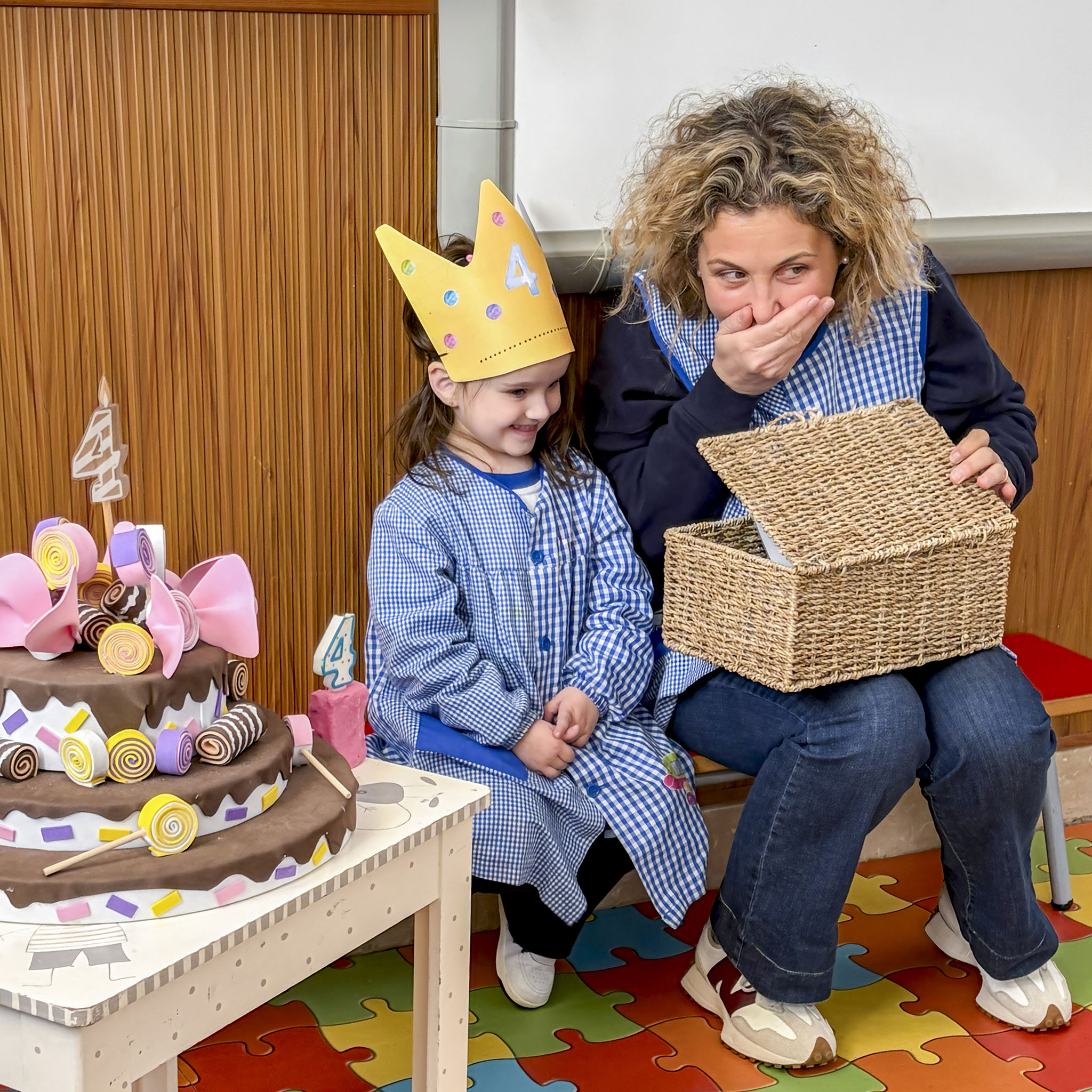 Una alumna d'educació infantil del col·legi concertat Beata Francinaina Cirer d'Inca (FECIB) somriu emocionada al costat de la seva mestra mentre descobreixen la capsa de les sorpreses durant el ritual d'aniversari de la celebració de la vida.