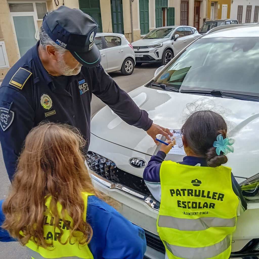 Els alumnes de 3r i 4t de primària del col·legi concertat Beata Francinaina Cirer d'Inca (FECIB) posen una multa simbòlica a un vehicle mal aparcat durant una activitat al carrer amb el policia tutor.